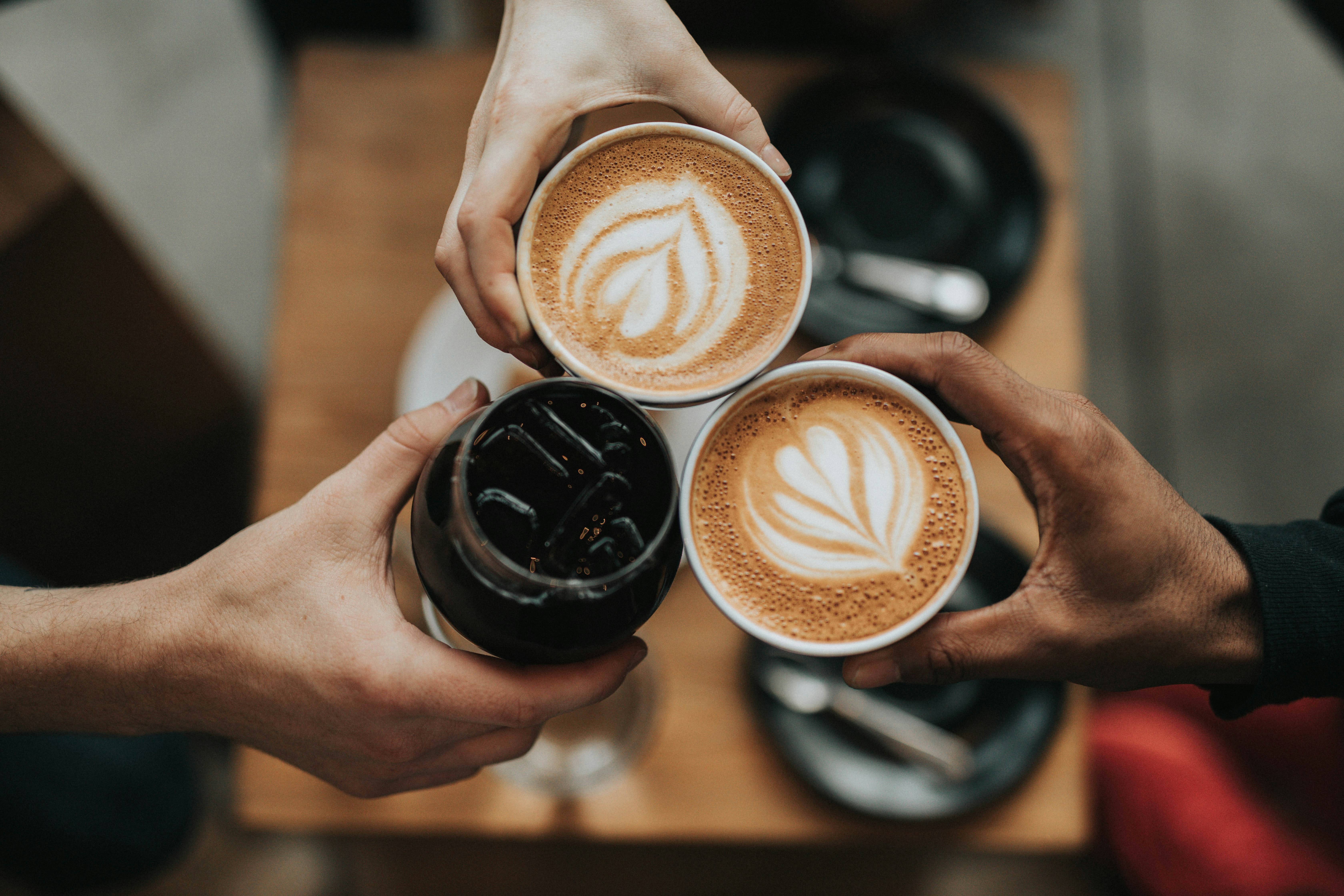 three persons holdng three coffees